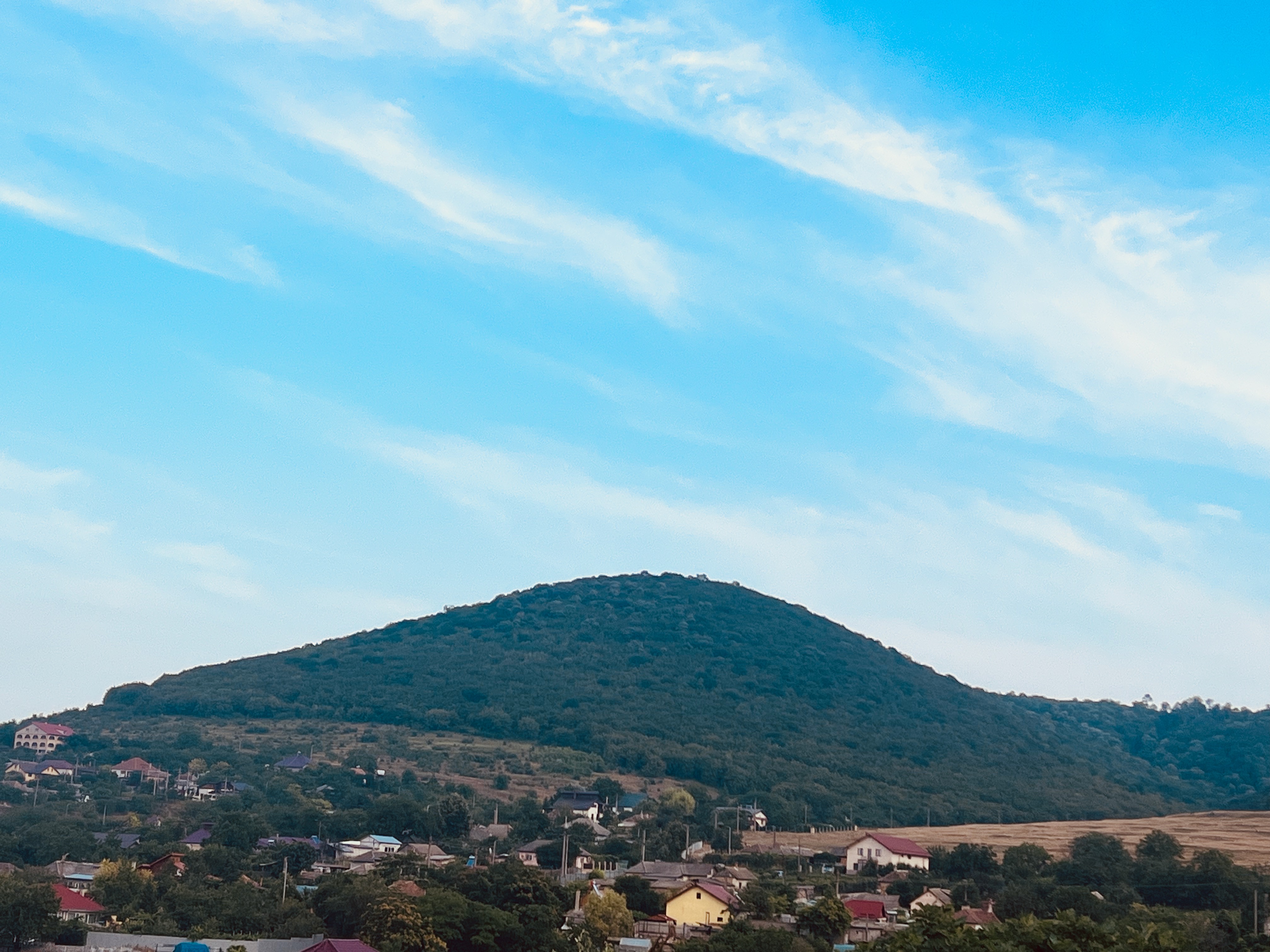 Vedere generală cu Babadag și Dealul Koyun Baba, care înseamnă „Tatăl Oilor” în turcă, Babdag, județul Tulcea, iulie 2023